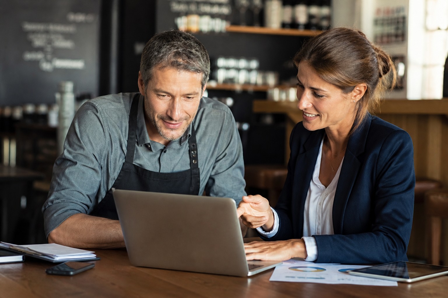 Local business owner and consultant reviewing business details on a laptop in a cafe